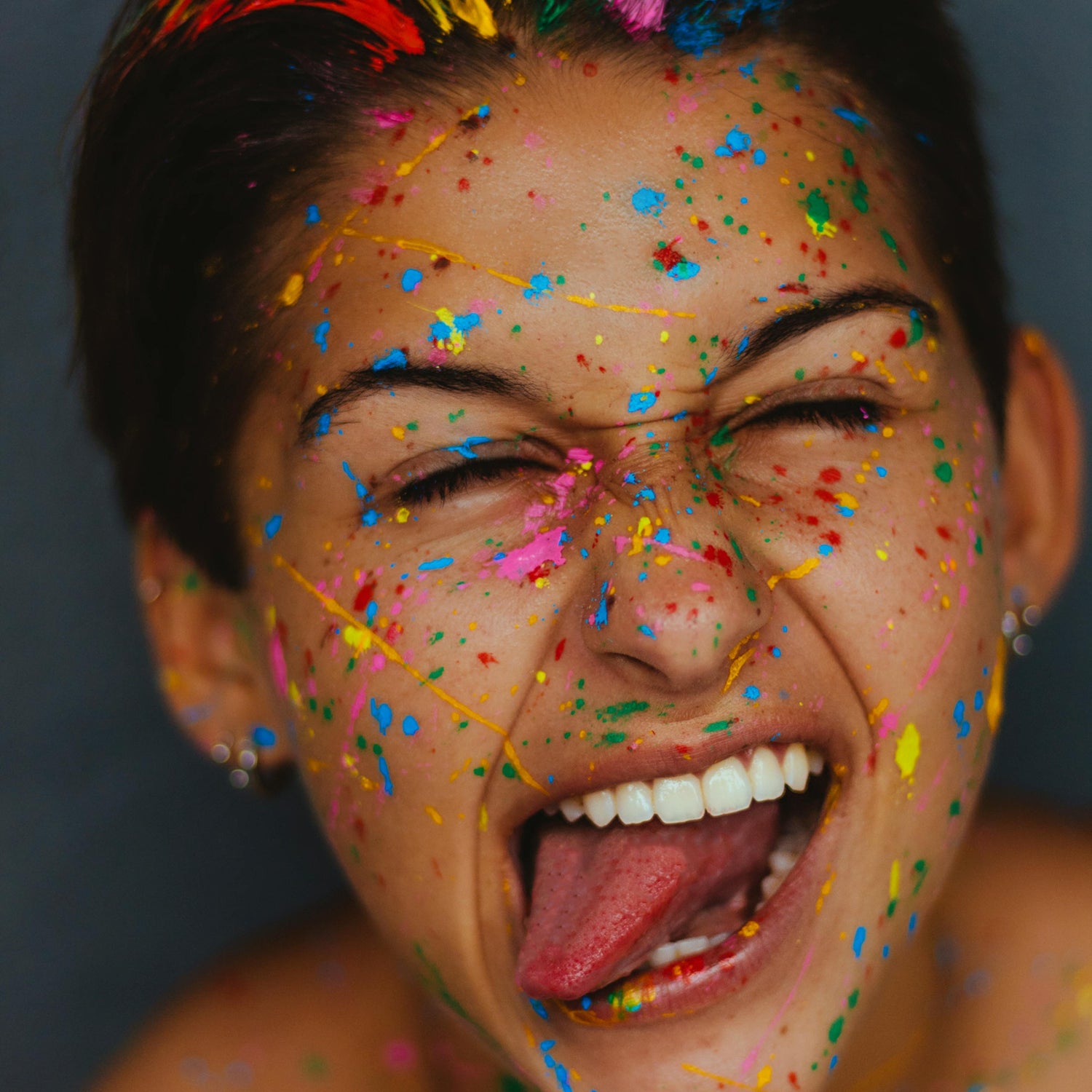 Person with colorful hair and face paint against a dark background